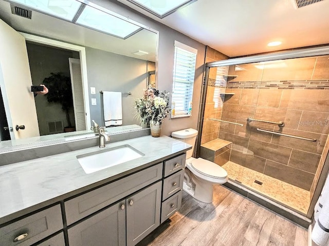 bathroom featuring hardwood / wood-style flooring, vanity, toilet, and a shower with door