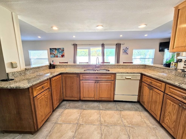 kitchen with kitchen peninsula, sink, white dishwasher, and a textured ceiling