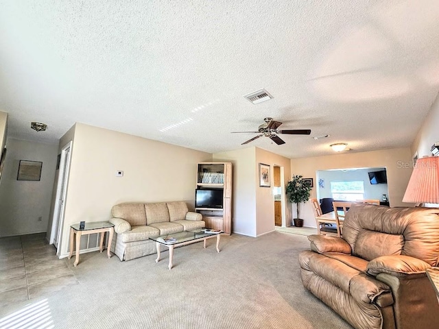 carpeted living room featuring ceiling fan and a textured ceiling