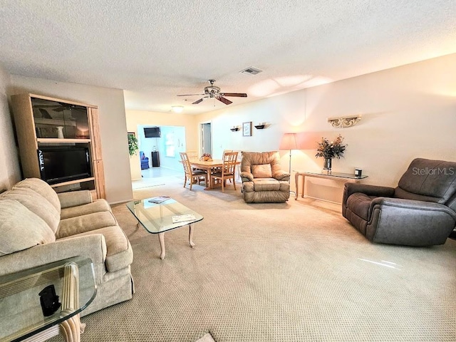 living room featuring a textured ceiling, carpet floors, and ceiling fan