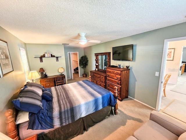 carpeted bedroom featuring ceiling fan, a walk in closet, and a textured ceiling