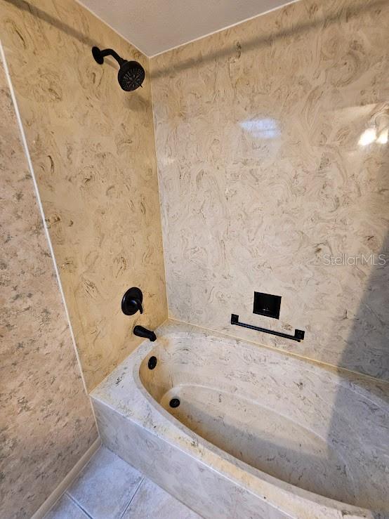 bathroom with tile patterned flooring and tiled shower / bath