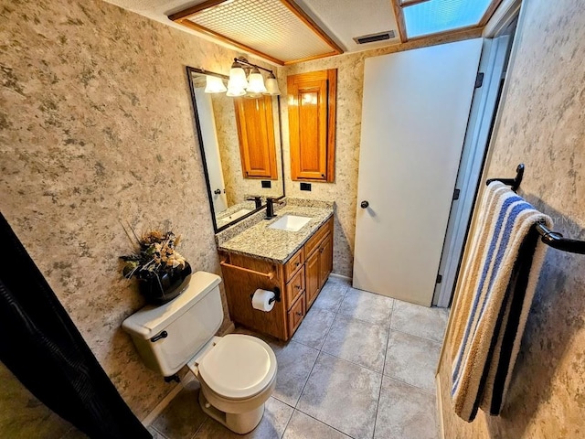 bathroom with toilet, vanity, and tile patterned floors