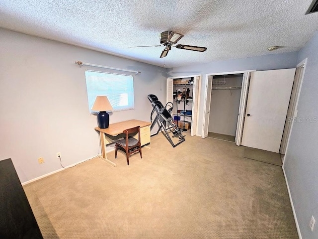 unfurnished office featuring a textured ceiling, ceiling fan, and light carpet