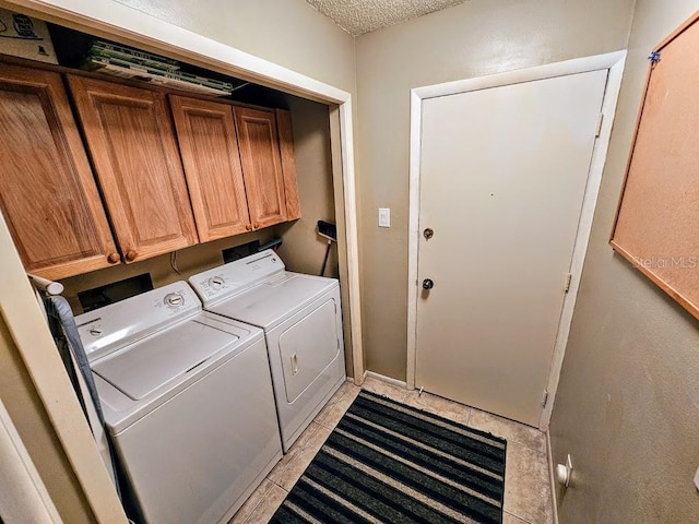 laundry room featuring light tile patterned flooring, cabinets, a textured ceiling, and washing machine and clothes dryer