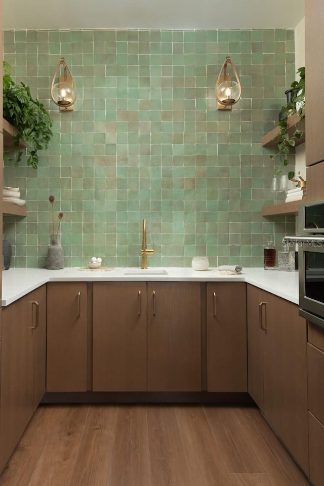 kitchen with backsplash, sink, and light hardwood / wood-style flooring