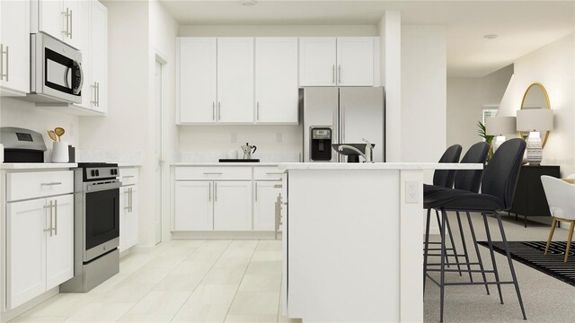 kitchen with appliances with stainless steel finishes, white cabinetry, a kitchen island with sink, and a breakfast bar area