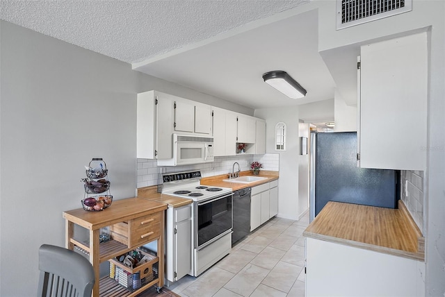 kitchen with white appliances, sink, decorative backsplash, a textured ceiling, and white cabinetry