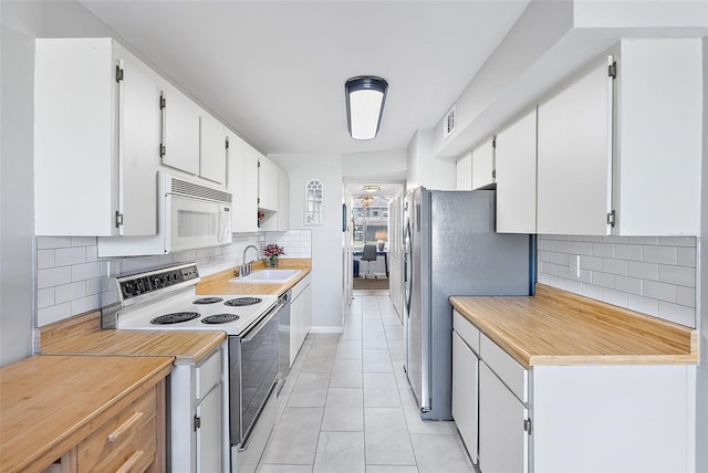4915 Bay St NE Unit 130, Saint Petersburg, FL 33703 - kitchen featuring white appliances, backsplash, light tile patterned floors, and white cabinets