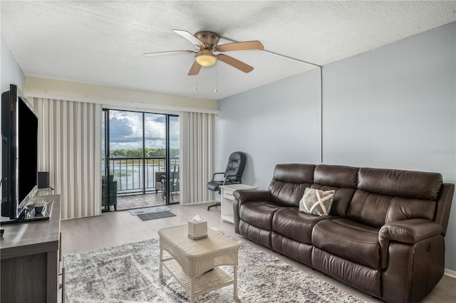 living room with hardwood / wood-style floors, a textured ceiling, and ceiling fan