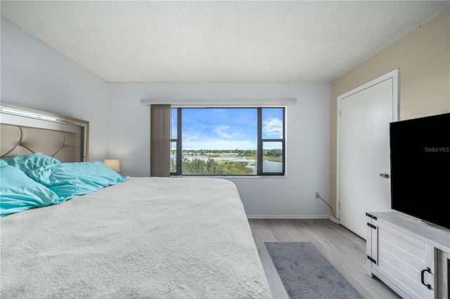 bedroom featuring light wood-type flooring and a textured ceiling