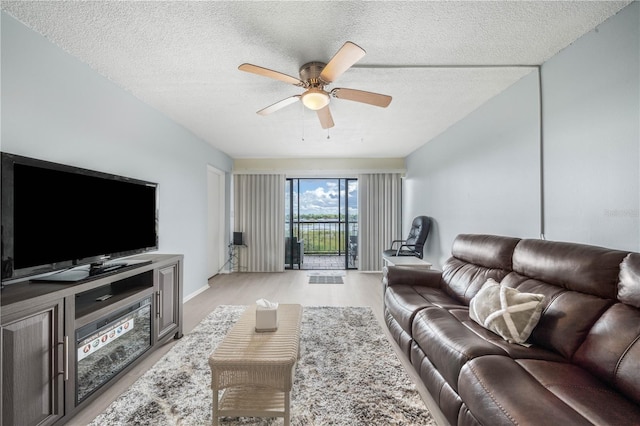 living room with a textured ceiling, light hardwood / wood-style floors, and ceiling fan