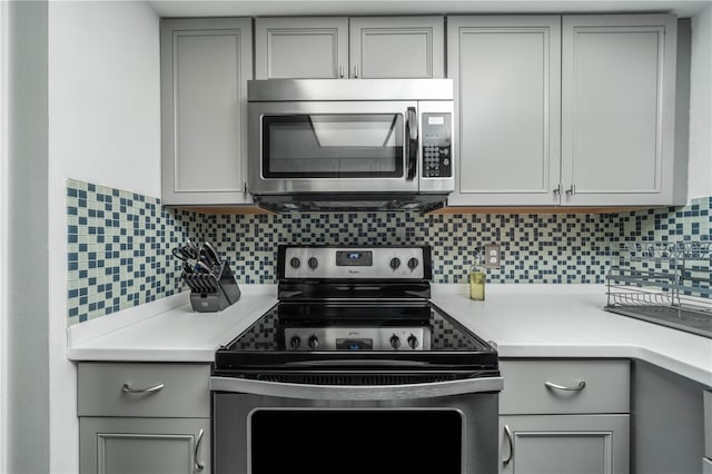 kitchen with backsplash, stainless steel appliances, and gray cabinetry