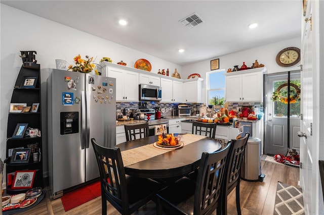 kitchen with decorative backsplash, wood-type flooring, stainless steel appliances, and white cabinetry