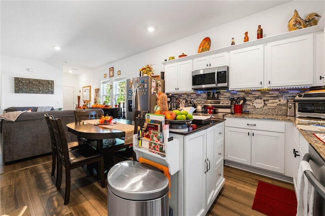 kitchen featuring white cabinetry, dark wood-type flooring, backsplash, dark stone countertops, and appliances with stainless steel finishes