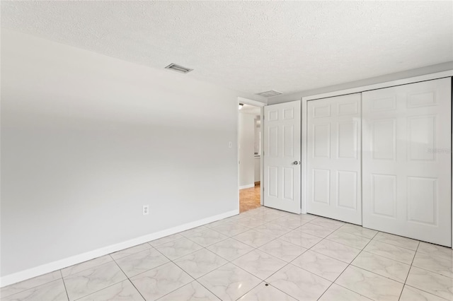 unfurnished bedroom featuring a textured ceiling and a closet