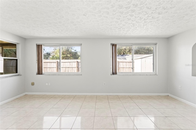 tiled empty room featuring a textured ceiling