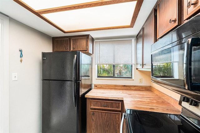 kitchen featuring decorative backsplash, wooden counters, and black appliances