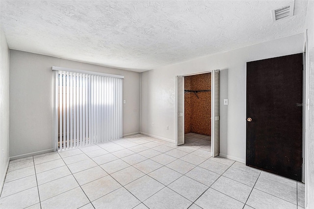 empty room with light tile patterned floors and a textured ceiling