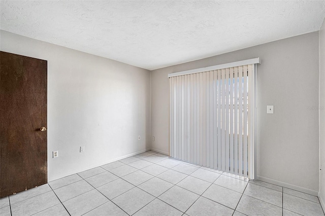 tiled empty room featuring a textured ceiling