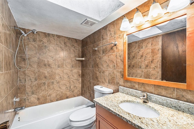 full bathroom featuring tasteful backsplash, vanity, tiled shower / bath combo, tile walls, and toilet