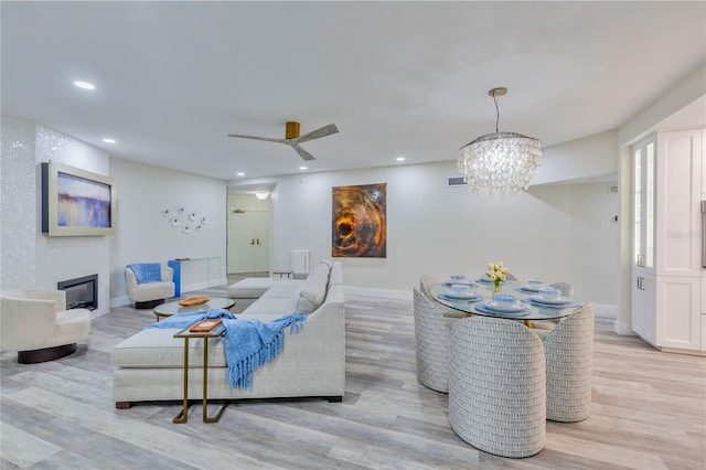 living room with ceiling fan with notable chandelier and light hardwood / wood-style floors