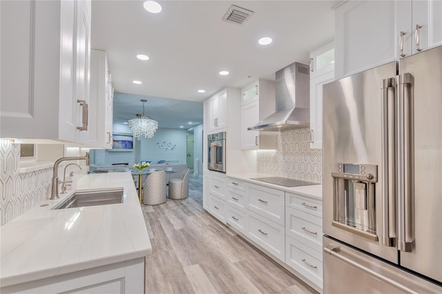 kitchen featuring sink, white cabinetry, wall chimney range hood, and stainless steel appliances