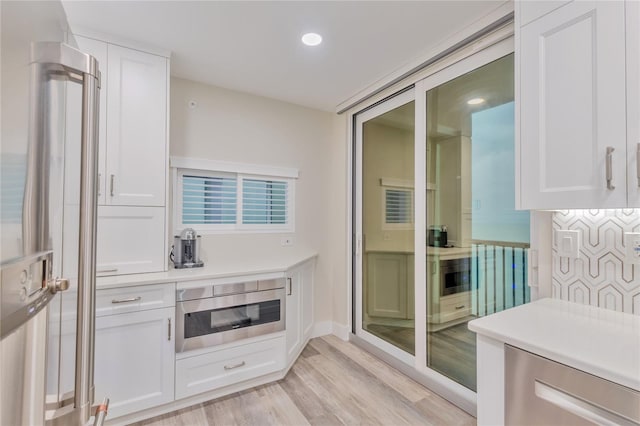 interior space with white cabinetry, light hardwood / wood-style flooring, and refrigerator