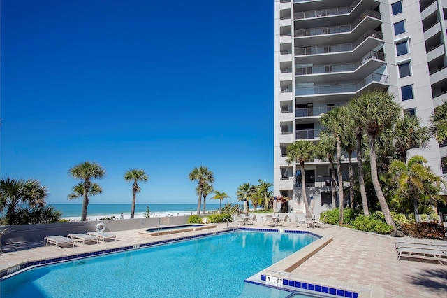 view of pool featuring a community hot tub, a water view, and a patio