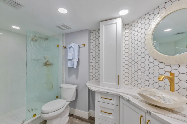 bathroom with toilet, vanity, decorative backsplash, hardwood / wood-style flooring, and a tile shower