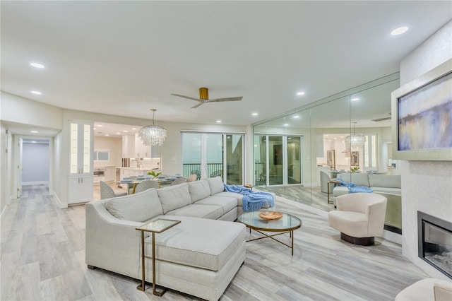 living room featuring ceiling fan, light hardwood / wood-style floors, and a fireplace