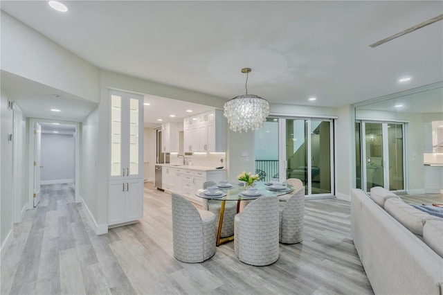 dining room with sink, light hardwood / wood-style flooring, and a chandelier