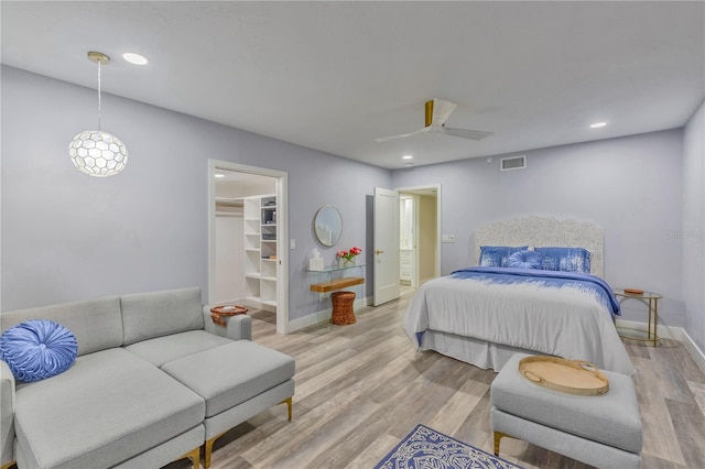 bedroom with ceiling fan, a closet, a walk in closet, and light hardwood / wood-style flooring