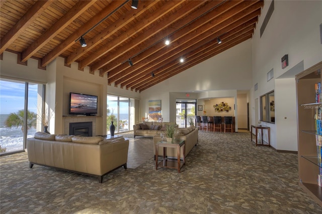 carpeted living room with wooden ceiling, beamed ceiling, and a towering ceiling