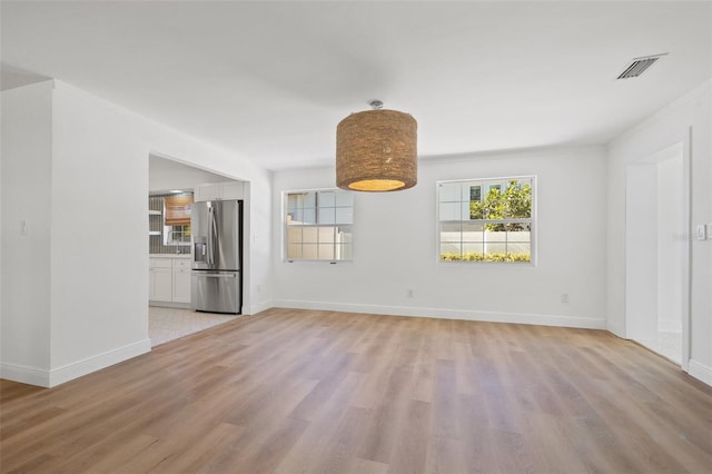 unfurnished living room featuring light wood-type flooring and ornamental molding