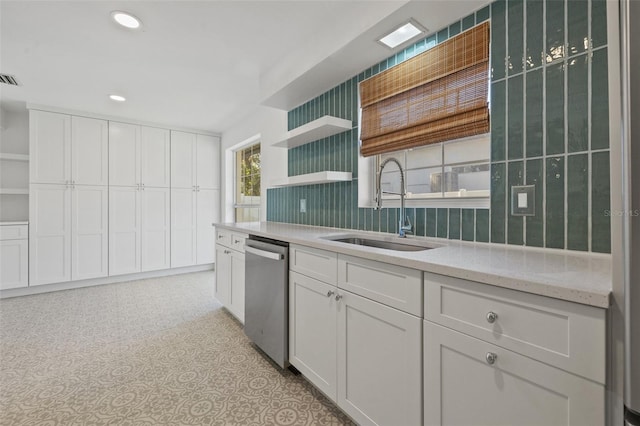 kitchen featuring dishwasher, light stone counters, white cabinetry, and sink