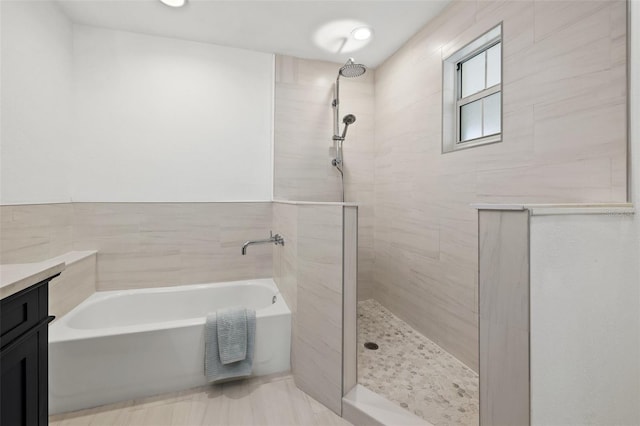 bathroom featuring vanity, shower with separate bathtub, and tile walls