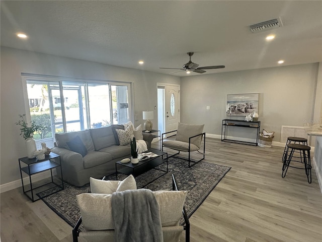 living room featuring ceiling fan, a textured ceiling, and light wood-type flooring