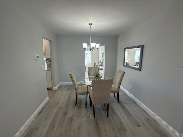 dining space featuring a chandelier, a textured ceiling, and light hardwood / wood-style floors