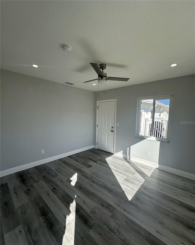 empty room featuring ceiling fan, dark wood-type flooring, and a textured ceiling