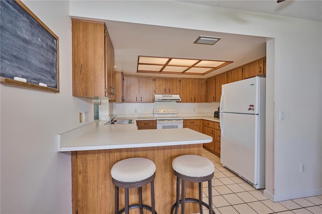 kitchen with ventilation hood, kitchen peninsula, white appliances, a breakfast bar area, and light tile patterned floors