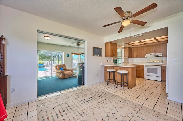 kitchen with a kitchen breakfast bar, kitchen peninsula, electric range, and light tile patterned flooring