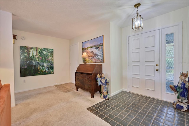 carpeted foyer featuring a textured ceiling and a chandelier