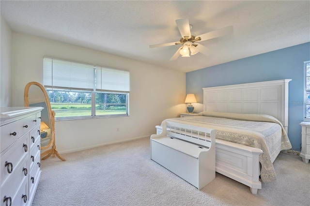 bedroom with ceiling fan, light colored carpet, and a textured ceiling