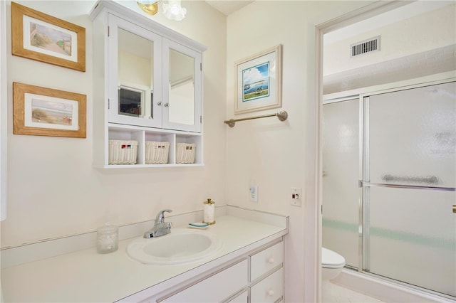 bathroom featuring vanity, toilet, and a shower with shower door