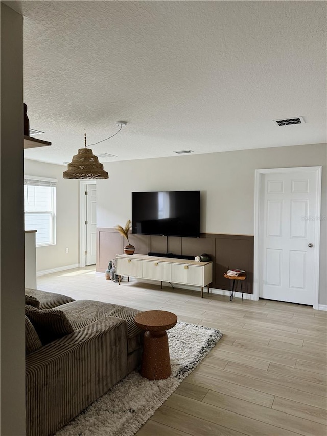 living room featuring light wood-type flooring and a textured ceiling