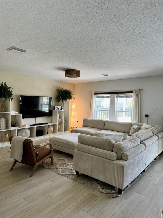 living room with a textured ceiling and light wood-type flooring