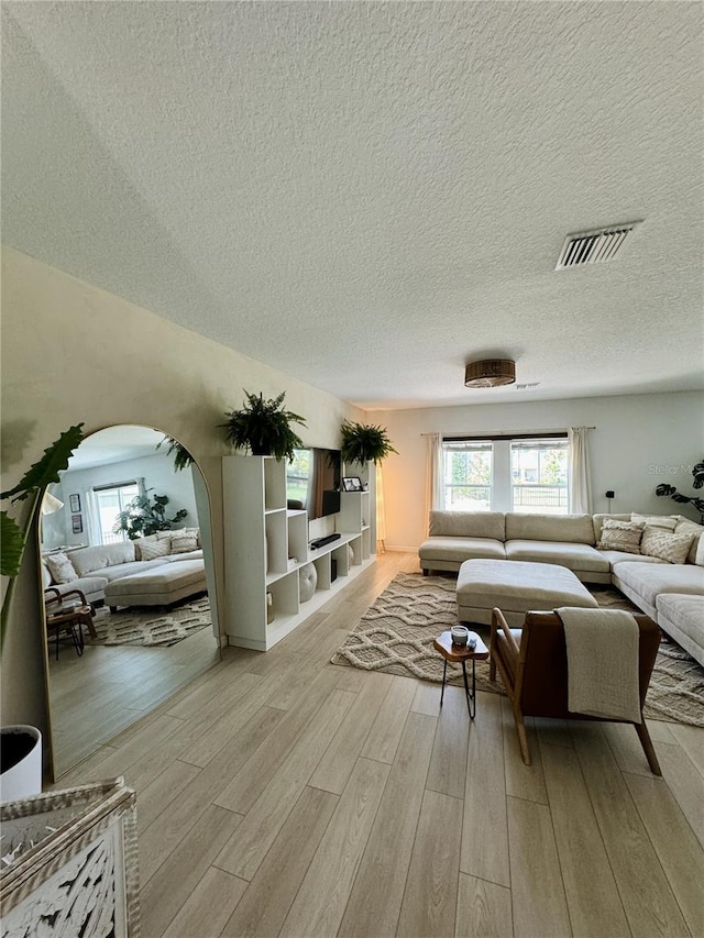 unfurnished living room featuring light hardwood / wood-style floors and a textured ceiling