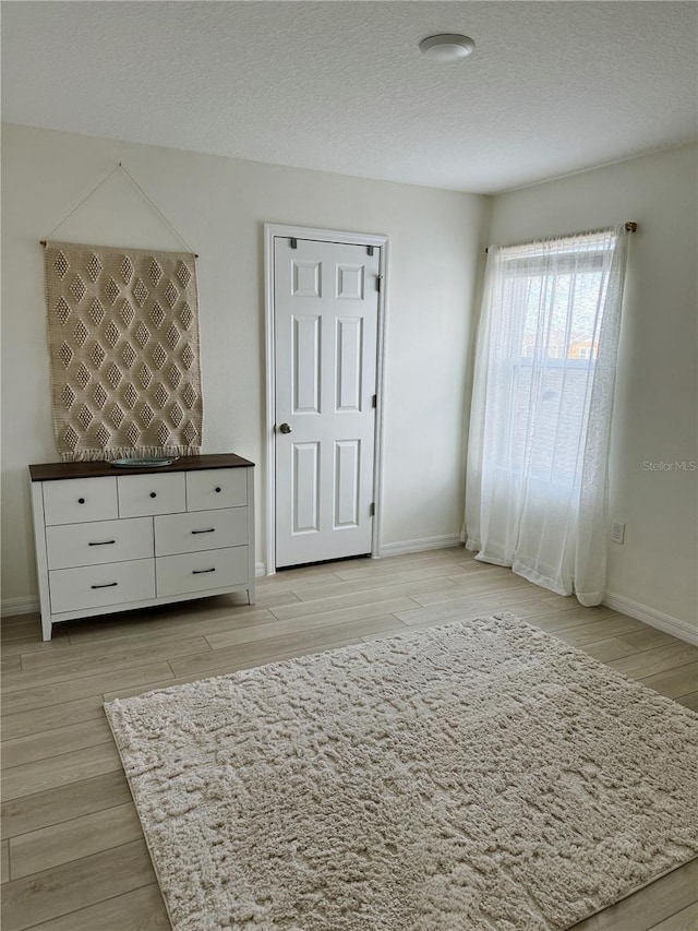 unfurnished bedroom with a textured ceiling and light wood-type flooring