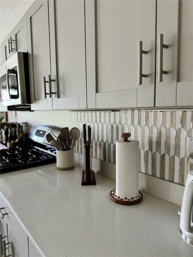 interior details with light stone counters, white cabinetry, and backsplash